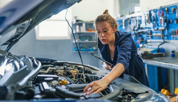 Mechanikerin überprüft Motorraum eines Autos