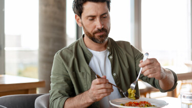 Mann isst Pesto-Nudeln