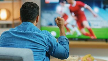 Fußballfan sitzt vor Fernseher und verfolgt Fußballspiel