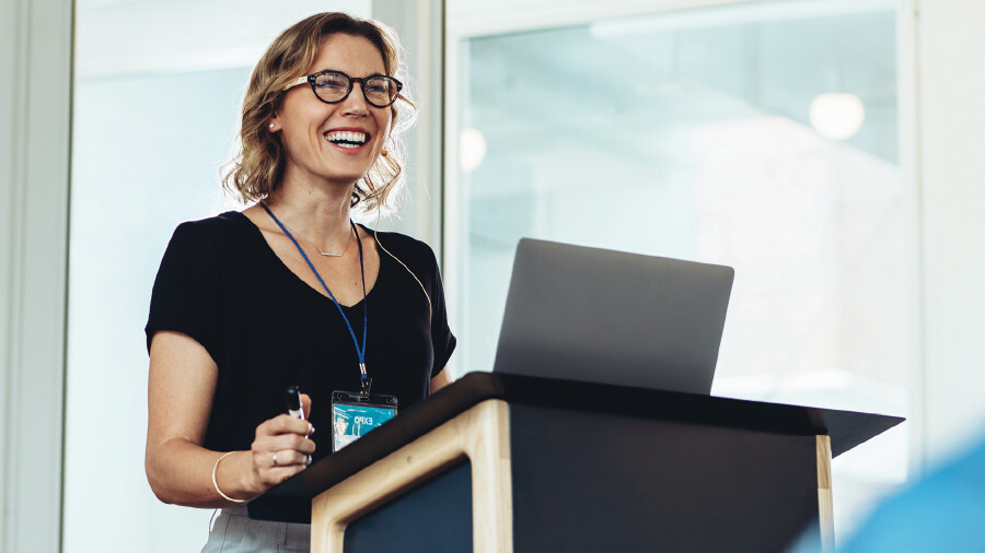 Eine Frau steht mit einem Laptop an einem Stehtisch