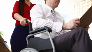 Mann im Rollstuhl wird von Frau geschoben