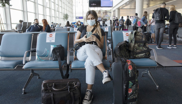 Junge Frau sitzt mit Mundnasenschutz in der Flughafenhalle © Gonzalo, stock.adobe.com