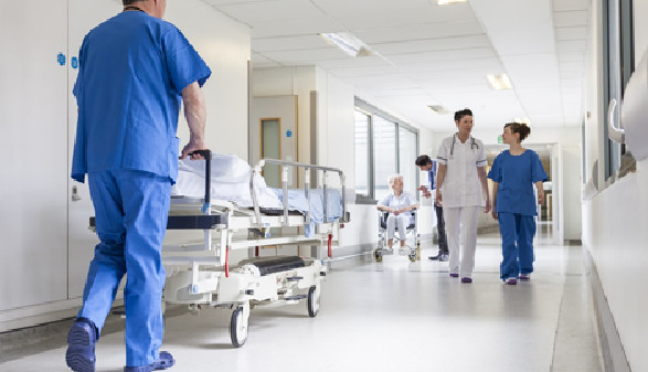 Pfleger schiebt Bett am Krankenhausflur