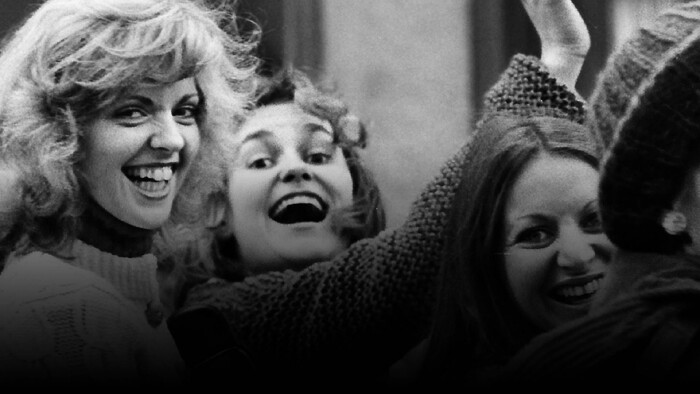 Drei lachende Frauen in einer Menschenmenge, schwarz-weiß Fotografie