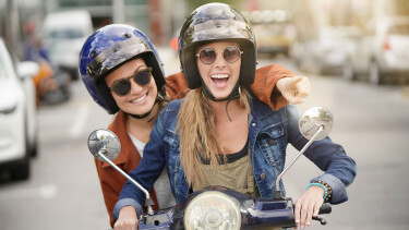 junge Frauen fahren gemeinsam auf Moped durch die Stadt