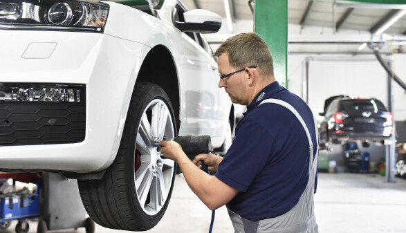 Mechaniker wechselt in einer Werkstatt Autoreifen.