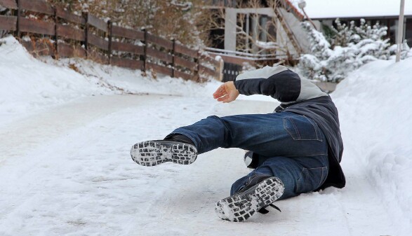 Person rutscht auf vereistem, verschneitem Weg aus und st&uuml;rzt.
