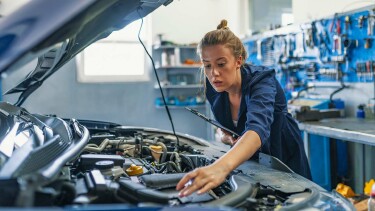 Mechanikerin überprüft Motorraum eines Autos