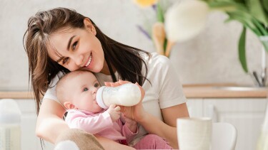 Frau f&uuml;ttert Baby mit der Flasche.