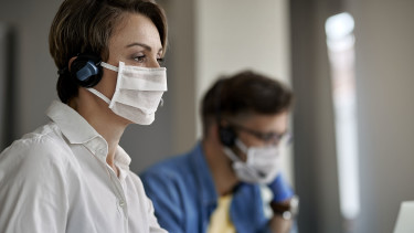 Mitarbeiterin in einem Callcenter mit Mund-Nasenschutz © Drazen, stock.adobe.com