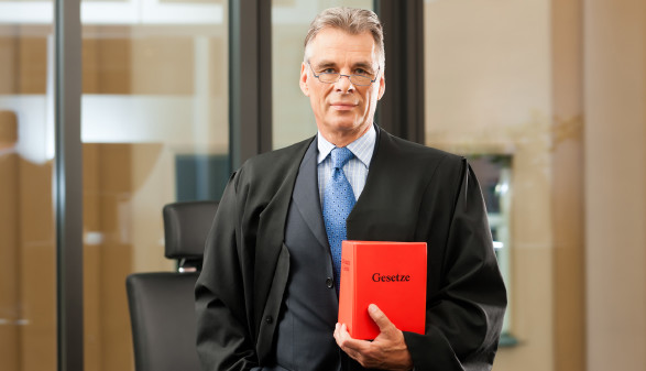 Anwalt mit Brille hält Gesetzbuch © Kzenon, stock.adobe.com