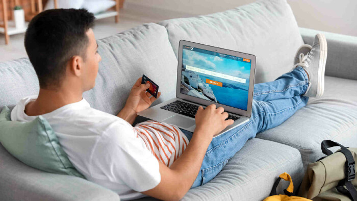 Mann auf der Couch bucht einen Flug online