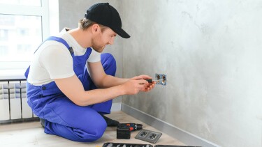 Elektriker installiert eine Steckdose in einer Wohnungswand.