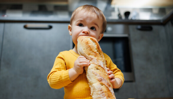 Baby mit Baguette in Küche