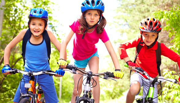 Drei Kinder mit Helm auf ihren Fahrr&auml;dern