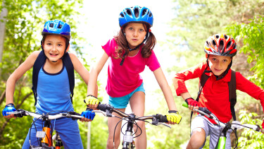 Drei Kinder mit Helm auf ihren Fahrr&auml;dern