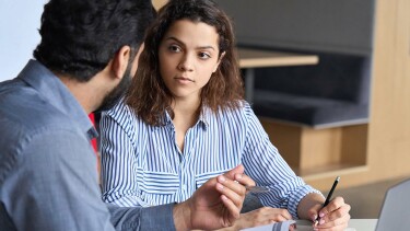 Junge Arbeitnehmerin diskutiert mit Arbeitskollegen