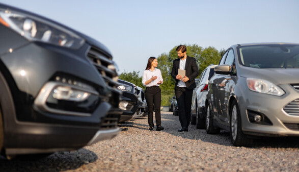 Ein Mann und eine Frau beim Gebrauchtwagenkauf am Schotterplatz
