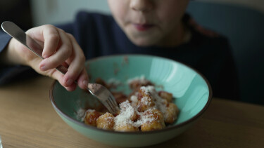 Ein Junge ist Gnocchi aus einem gr&uuml;nen Suppenteller