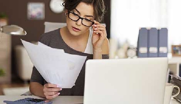 Frau mit Brille sitz vor Ihrem Laptop und prüft Unterlagen © Fotolia.com, gpointstudio