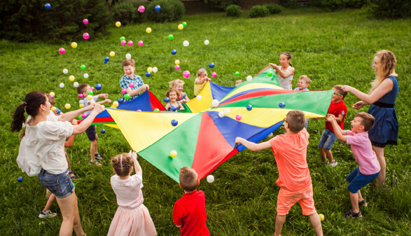 Kinder und Betreuerinnen stehen im Kreis auf einer Wiese