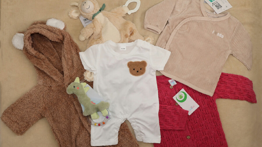 Babykleidung auf beigem Hintergrund