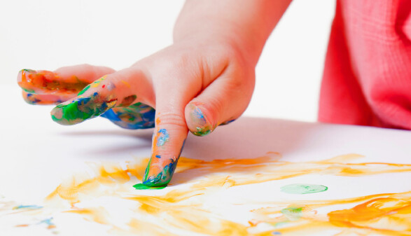 Kind malt mit Fingerfarben