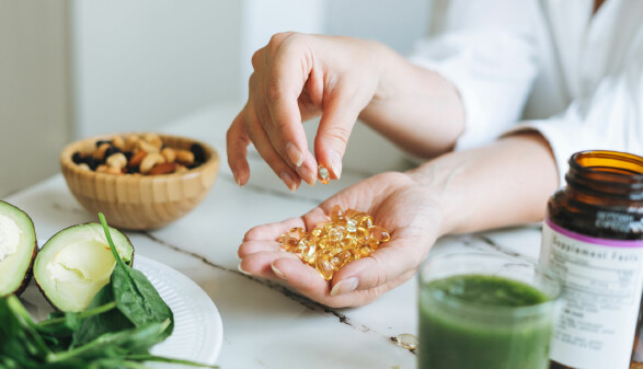 Die Hand einer Frau, sie h&auml;lt eine Vielzahl von Vitamin-D-Kapseln.