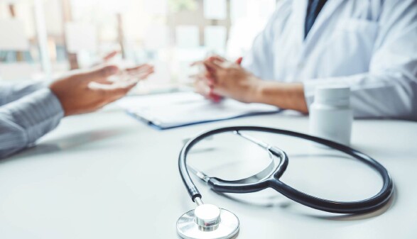 Hände von Arzt und Patient, ohne Gesicht. Vorne Stethoskop