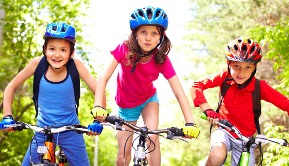 Drei Kinder mit Helm auf ihren Fahrr&auml;dern