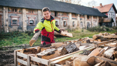 Ein junger Mann schlichtet Brennholz in Kisten.