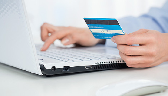 Jemand tippt Daten der Kreditkarte in Laptop