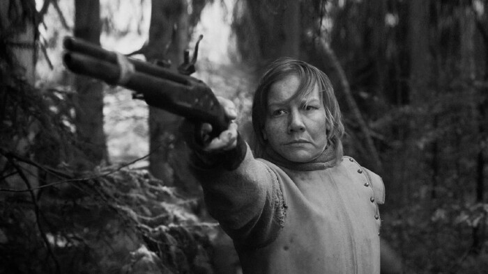 Person zielt mit einer Schusswaffe in einem bewaldeten Gebiet.