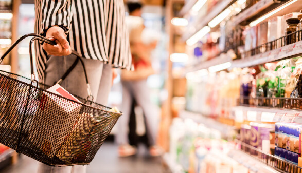 Eine Frau mit einem Einkaufskorb im Supermarkt. 