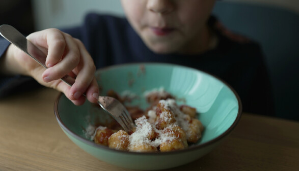 Ein Junge ist Gnocchi aus einem gr&uuml;nen Suppenteller