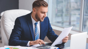 Mann sitzt im Büro und rechnet mit seinem Taschenrechner © Pixel-Shot, stock.adobe.com