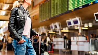 Frau mit Koffer schaut auf Monitor mit Abflugzeiten © -, panthermedia
