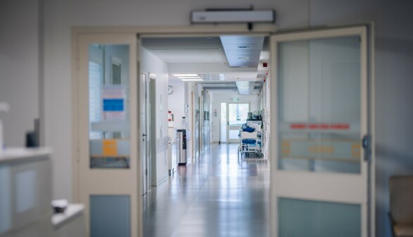 Eine T&uuml;r ist offen, es ist ein leerer Gang in einem Krankenhaus zu sehen. Keine Menschen sind auf dem Foto.