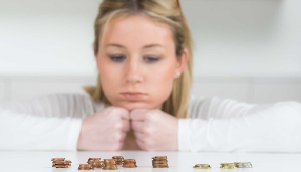 Frau mit traurigem Blick auf Geldmünzen