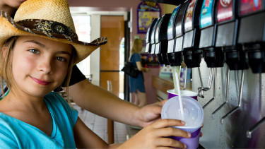 Mädchen hält Becher unter Getränkeautomat © Eléonore H , stock.adobe.com