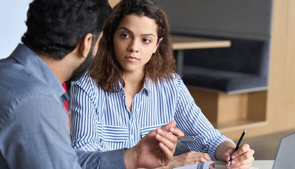 Junge Arbeitnehmerin diskutiert mit Arbeitskollegen