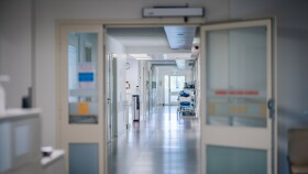 Eine T&uuml;r ist offen, es ist ein leerer Gang in einem Krankenhaus zu sehen. Keine Menschen sind auf dem Foto.