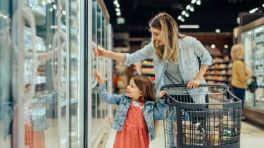 Frau und Kind mit Einkaufswagen vor dem Tiefk&uuml;hlregal im Supermarkt,