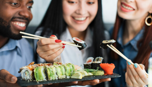 Ein Mann und zwei Frauen essen Sushi.
